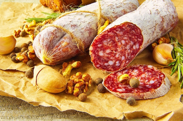 Salami italien avec sel de mer, romarin, ail et noix sur papier style rustique gros plan