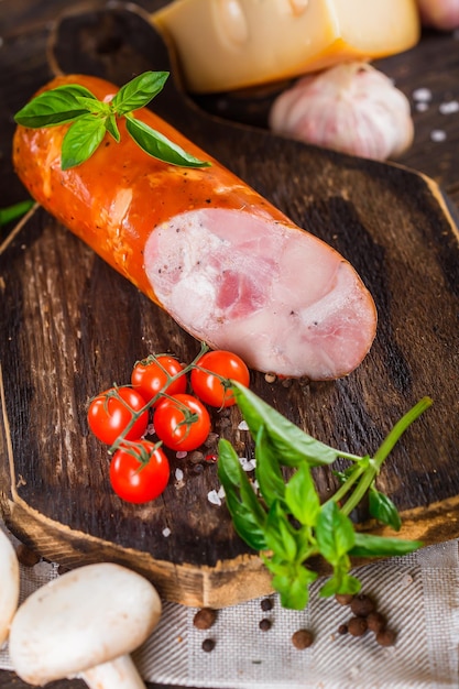 salami avec morceaux de saindoux, entier et morceau, tomates cerises, fromage et épices, planche à découper de cuisine