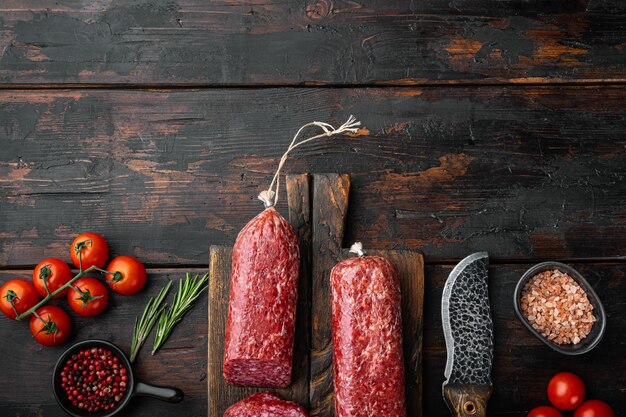 Salami, saucisse fumée au salami, ensemble en tranches, sur une vieille table en bois foncé, vue de dessus à plat