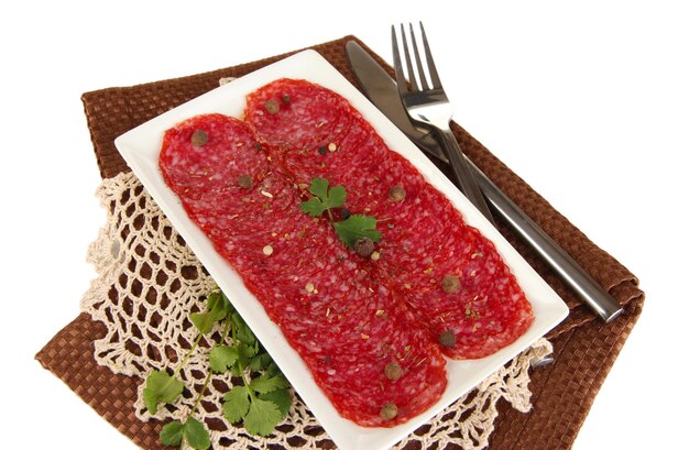 Salami savoureux sur plaque sur serviette isolé sur blanc