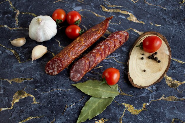 Salami tranché appétissant sur marbre noir et tomates cerises