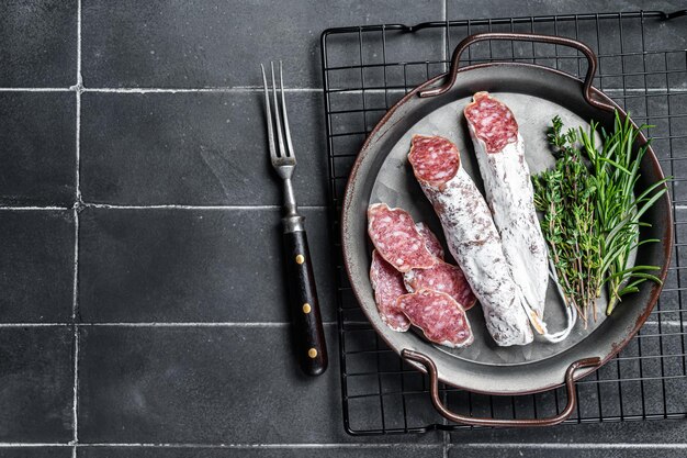 Photo salami en tranches dans un plateau en acier saucisse espagnole traditionnelle fond noir vue supérieure espace de copie