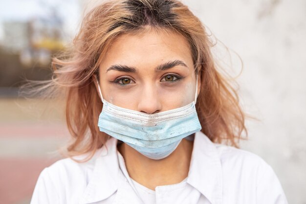 Sale infirmière fatiguée avec de la cendre sur le visage assise à l'extérieur de l'hôpital