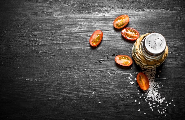 Salière avec les tomates hachées sur le tableau noir