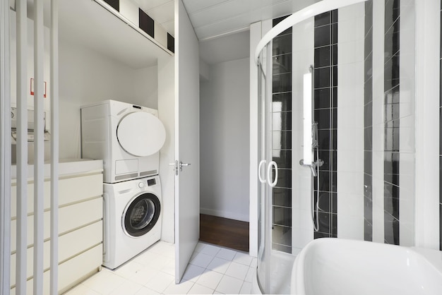 Salle de bain avec armoires blanches cabine de douche vitrée et laveuse et sécheuse blanches