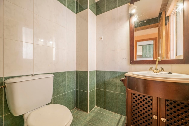 Salle de bain avec armoires en bois de couleur claire et carreaux de couleur rougeâtre et crème