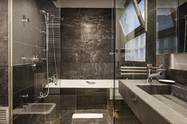 Photo salle de bain dans les tons gris et noir avec vasque monobloc en marbre gris intégré pare douche miroir avec porte vitrée et carrelage ardoise