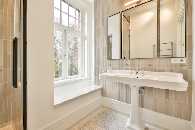 Salle de bain avec lavabo en céramique sous le miroir et une petite fenêtre dans une maison moderne