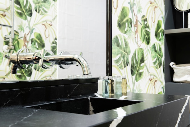 Salle de bain avec lavabo en marbre noir avec robinet chromé veiné blanc encastré dans le miroir