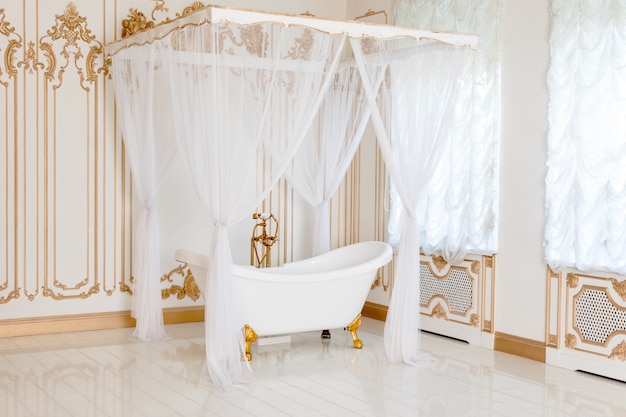 Salle de bain de luxe aux couleurs claires avec des détails de meubles dorés et auvent. Intérieur classique élégant.