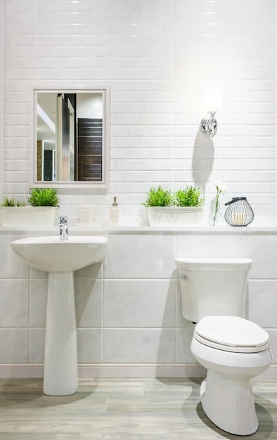 Salle de bain moderne et spacieuse avec des carreaux lumineux avec toilette et lavabo