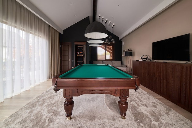 Salle de billard moderne avec une belle table et de grandes fenêtres.