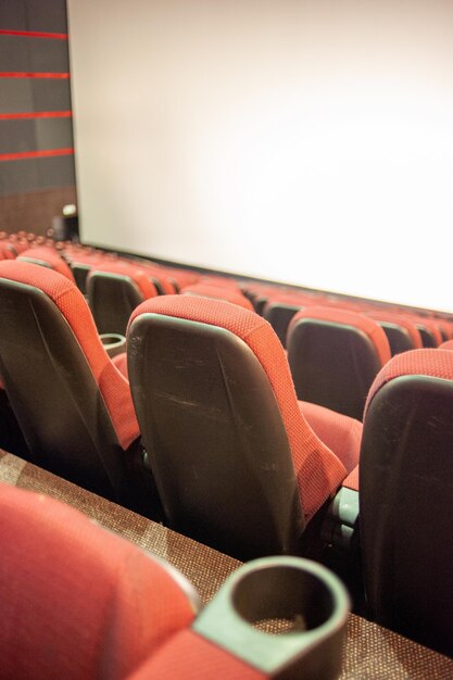 Une salle de cinéma avec des sièges rouges et un écran blanc