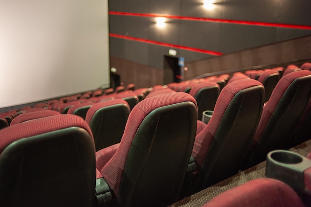 Une salle de cinéma avec des sièges rouges et un écran blanc