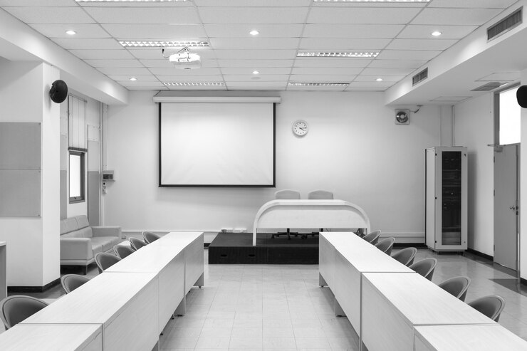 Photo salle de conférence intérieure avec panneau de projection blanc.