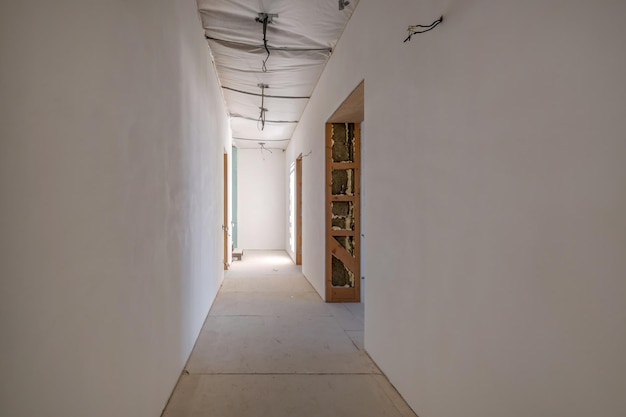 Salle de couloir vide non meublée avec un minimum de réparations préparatoires à l'intérieur avec des murs blancs et des cloisons sèches