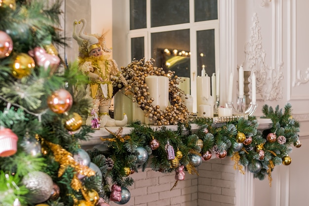 salle éclairée avec des guirlandes décorées prête à fêter Noël. Design d'intérieur de chambre de Noël, arbre de Noël décoré par des lumières, des bougies et des guirlandes d'éclairage à l'intérieur de la cheminée.