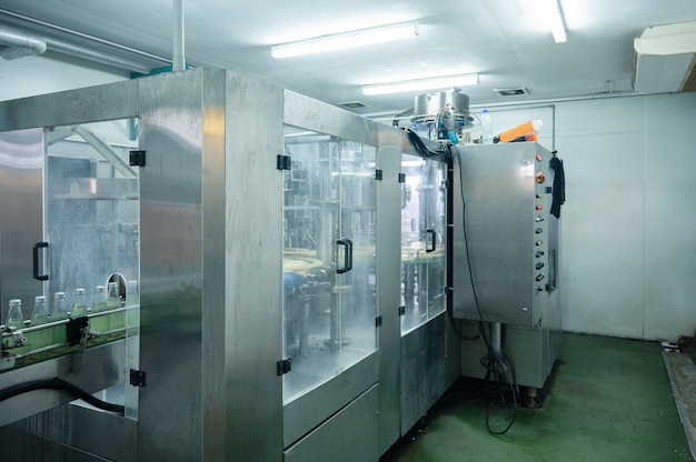 Salle d'embouteillage des boissons avec machines automatiques et panneau de commande dans la ligne de production de l'usine de transformation des boissons