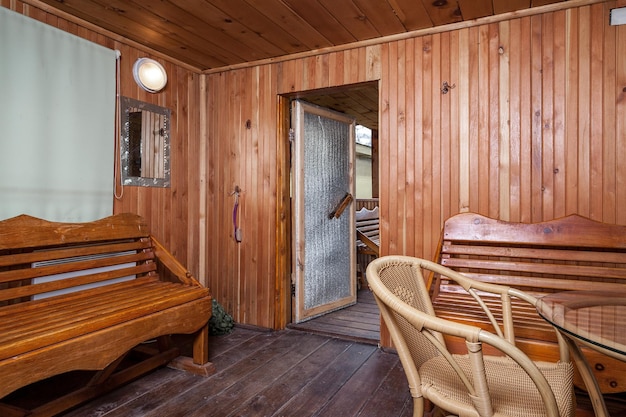 Une salle de loisirs devant l'entrée des bains publics dans un style en bois avec plusieurs bancs