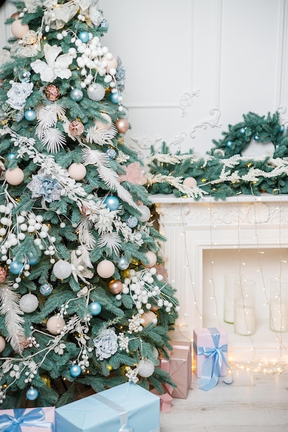 Une salle lumineuse joliment décorée pour les cadeaux du sapin de Noël du Nouvel An sous le sapin la cheminée est décorée de guirlandes
