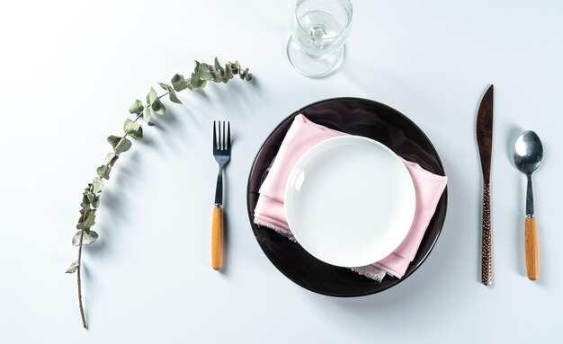 Salle à manger avec assiette vide placée avec un couteau et une fourchette sur fond blanc