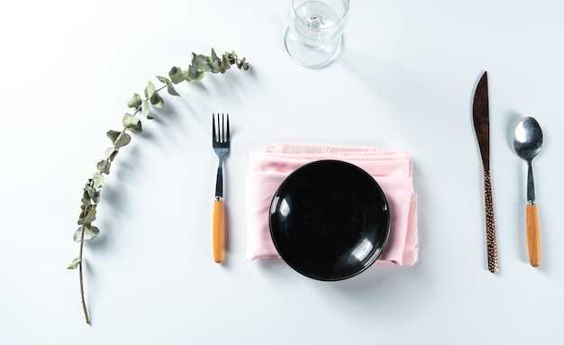 Salle à manger avec assiette vide placée avec un couteau et une fourchette sur fond blanc