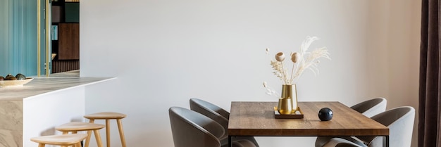 Salle à manger moderne et vintage avec table en bois marron, chaises grises et lustre élégant Mur blanc minimaliste Accessoires créatifs