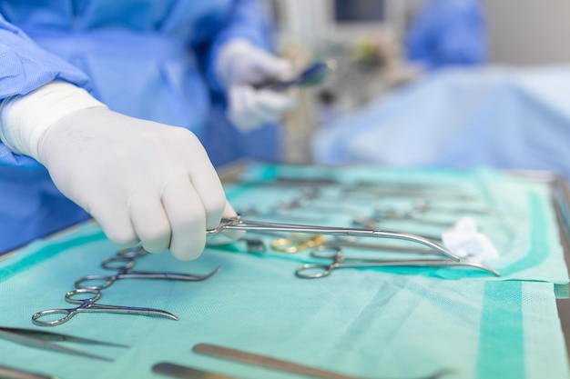 Salle d'opération de la table chirurgicale avec instruments L'assistant ramasse les instruments pour les chirurgiens pendant l'opération Chirurgie en cours Médecins professionnels exécutant la chirurgie