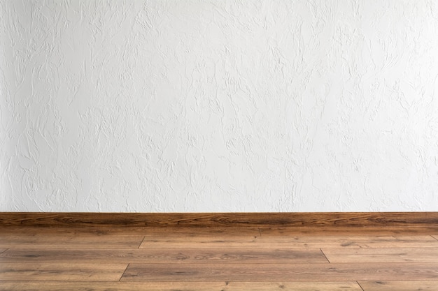 Salle vide avec mur blanc et parquet. Design intérieur minimal.