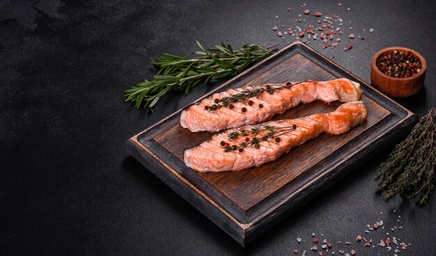 Photo salmon grillé avec des herbes servi sur une table en béton noir