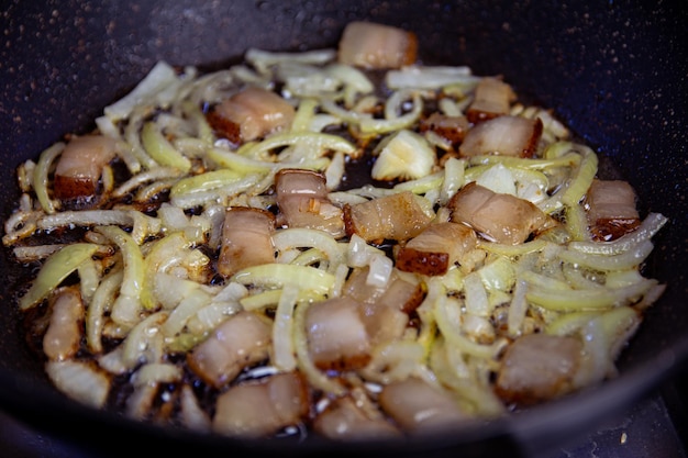 Salo et oignon finement haché sont frits dans une poêle noire