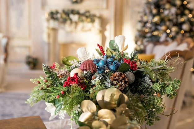 Salon Arbre de Noël, cheminée contemporaine, appartement design intérieur loft. composition de table, vase en sapin avec neige artificielle, boules, arcs, perles contre l'intérieur festif