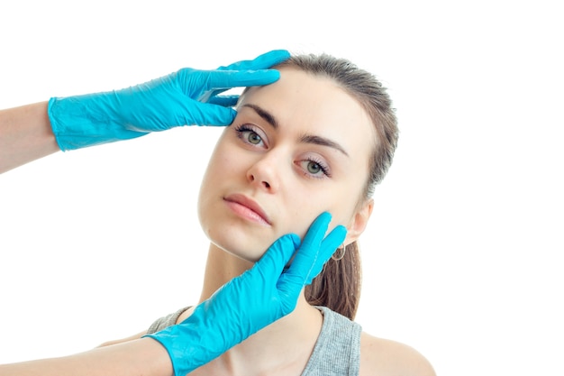 Salon de beauté esthéticienne garde une personne jeunes filles dans des mains gantées de bleu isolé sur fond blanc