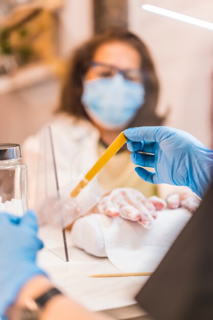 Salon de beauté, réouverture de l'entreprise après la pandémie de coronavirus. Un client avec un masque facial recevant un traitement sur ses mains. Covid-19