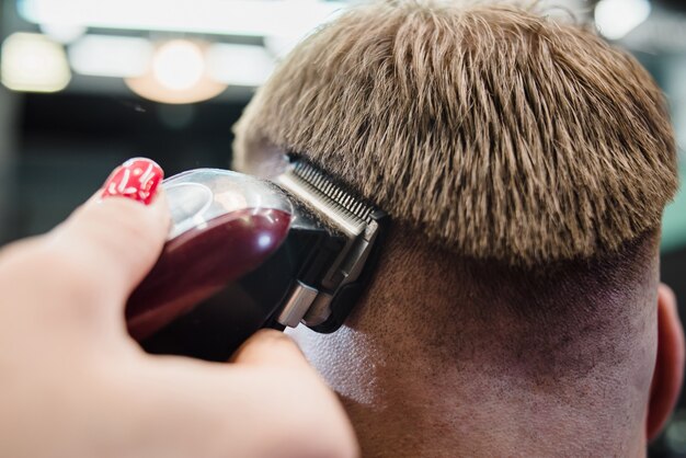 Salon de coiffure belle fille coupe un homme barbu dans le salon