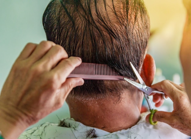 Salon de coiffure coupe les cheveux gris d&#39;un homme asiatique âgé