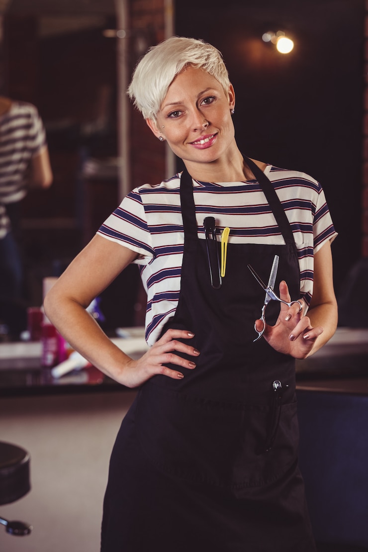 Photo salon de coiffure féminine debout avec la main sur la hanche dans un salon