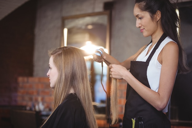 Salon de coiffure féminine lissant les cheveux d'un client