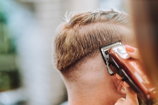 Salon de coiffure fille sèche les cheveux à un homme dans un salon