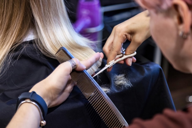 Salon de coiffure gros plan femme coiffeur faire une jolie coiffure à la mode pour une jolie petite fille blonde enfant dans un salon de coiffure moderne