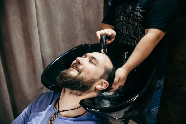 Salon de coiffure, un homme avec une barbe coupe coiffeur