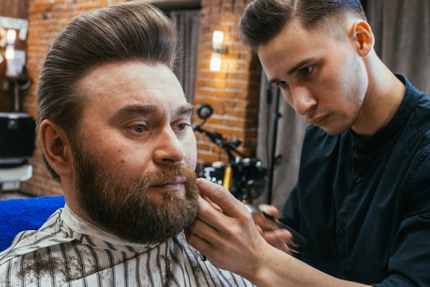 Salon de coiffure, un homme avec une barbe coupe coiffeur