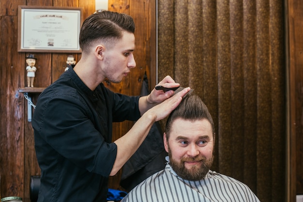 Salon de coiffure, un homme avec un coiffeur à barbe. Beaux cheveux et soins, salon de coiffure pour hommes. Coupe de cheveux professionnelle, coiffure et style rétro. Service Clients. Russie, Sverdlovsk, 12 février 2018