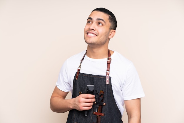 Salon de coiffure homme dans un tablier sur mur beige rire et levant