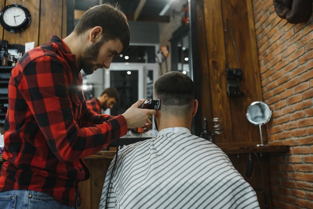 Photo salon de coiffure. homme avec femme dans la chaise de barbier, coiffeur barbershop coiffant ses cheveux