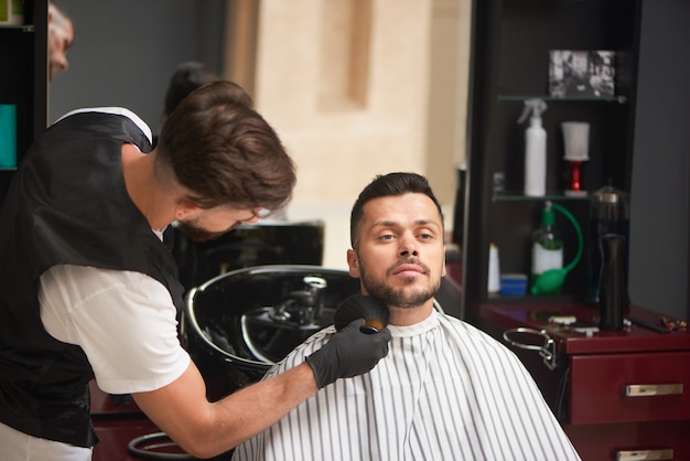 Salon de coiffure masculin toilettage de la barbe du client avec une brosse.