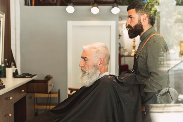 Salon de coiffure préparant une coupe de cheveux client âgé barbu