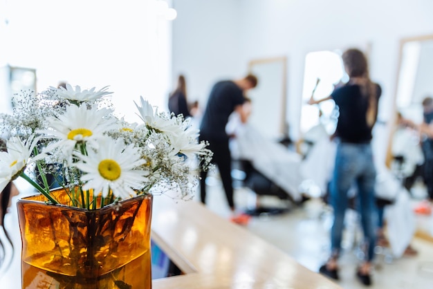 Salon de coupe de cheveux sur fond de camomille dans un vase en gros plan