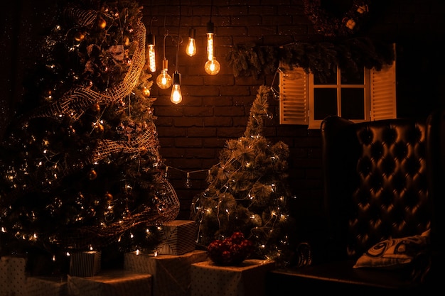 Salon joliment décoré avec un arbre de Noël avec un fauteuil vintage en cuir avec de vieilles lampes jaunes avec des cadeaux de Noël et des jouets le soir.