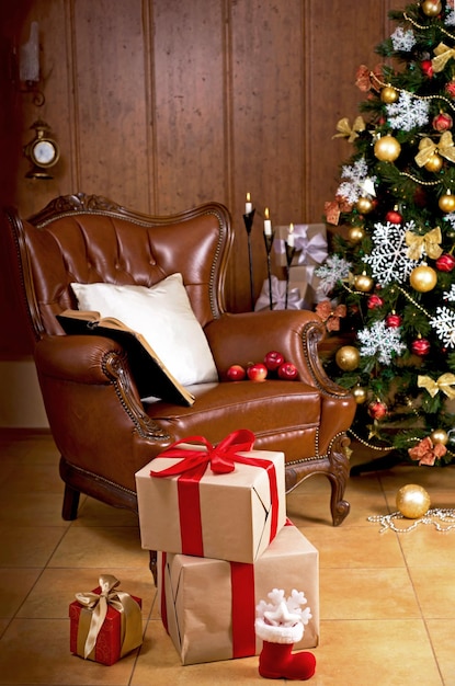 Le salon de la maison est décoré pour Noël Sapin de Noël décoré pour les vacances et beaucoup de cadeaux à côté Fauteuil rétro dans la maison